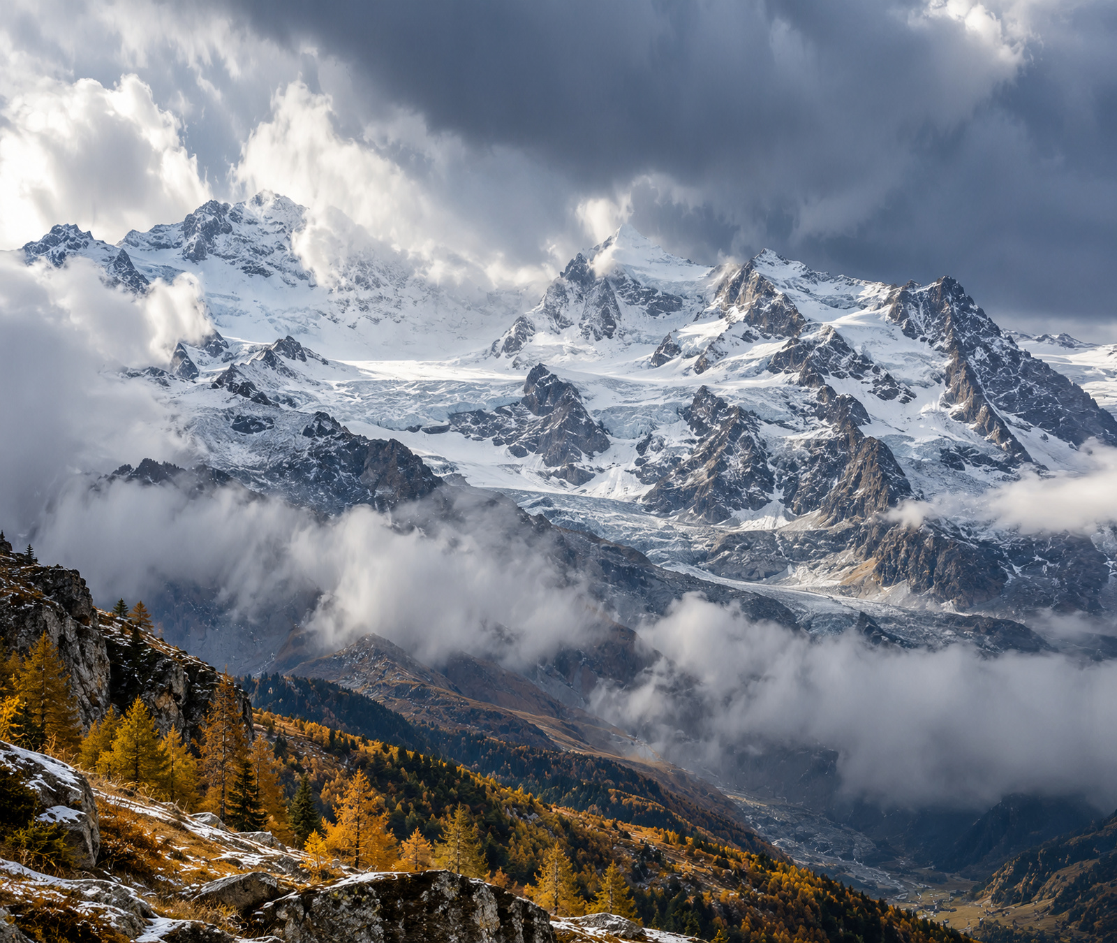 Immagine simbolica delle Alpi occidentali italiane con grandi cime innevate, ghiacciai e pendii autunnali sotto nubi fredde.
