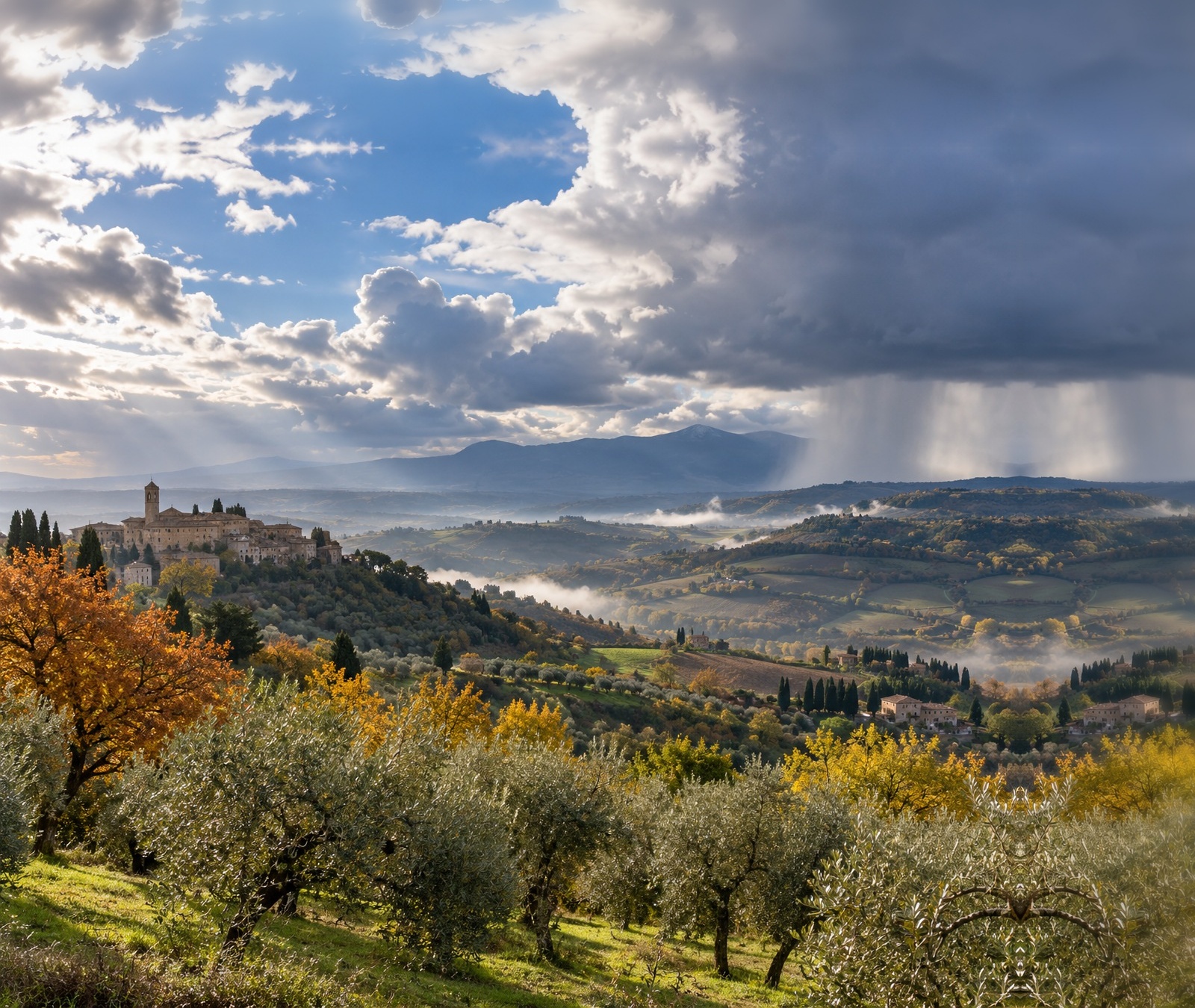 Paesaggio collinare italiano con cielo variabile e rovesci in lontananza come immagine simbolica del tempo instabile a tratti.